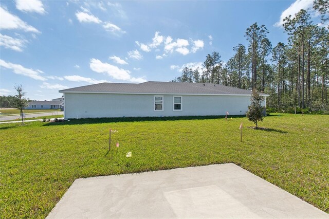 view of side of property with a patio area, a lawn, and stucco siding