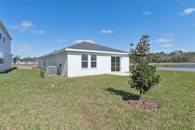 back of house with stucco siding, cooling unit, and a yard