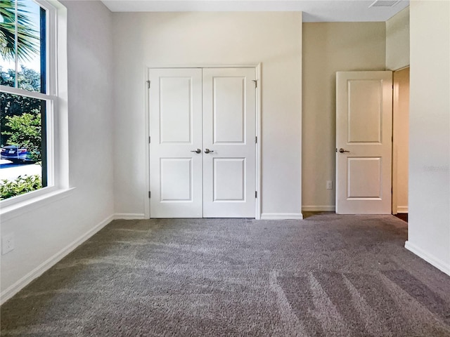 unfurnished bedroom featuring dark carpet and a closet