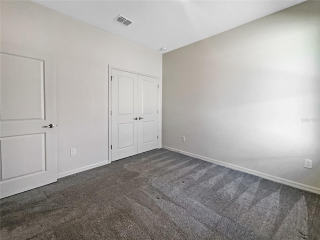 unfurnished bedroom featuring dark carpet and a closet