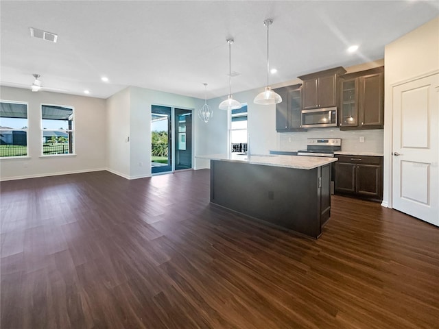 kitchen with hanging light fixtures, decorative backsplash, a kitchen island, dark hardwood / wood-style flooring, and stainless steel appliances