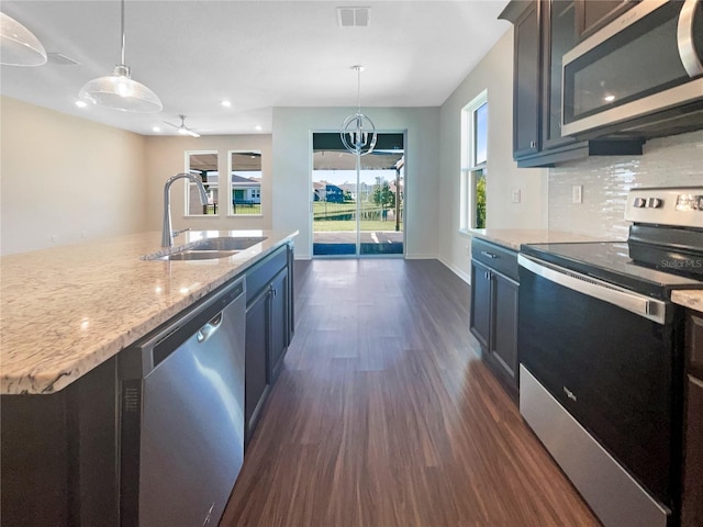 kitchen featuring stainless steel appliances, ceiling fan, sink, pendant lighting, and a center island with sink