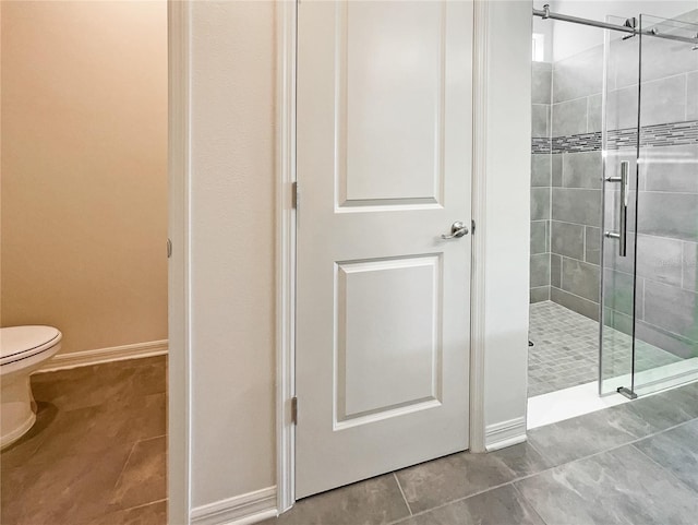 bathroom featuring tile patterned flooring, a shower with shower door, and toilet