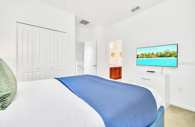 bedroom with a closet, carpet, and ensuite bath