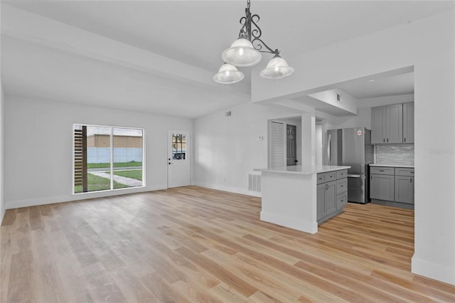 kitchen featuring stainless steel fridge, backsplash, gray cabinets, a center island, and light hardwood / wood-style floors