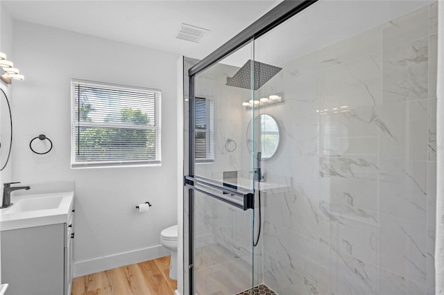 bathroom featuring hardwood / wood-style floors, walk in shower, vanity, and toilet