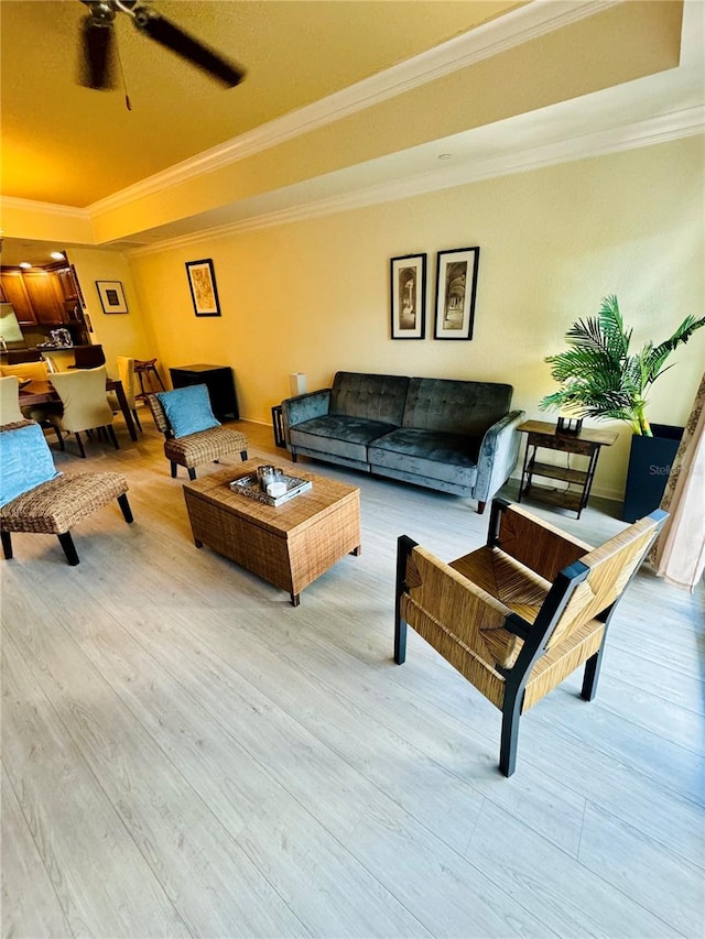 living room with hardwood / wood-style flooring, a raised ceiling, crown molding, and ceiling fan