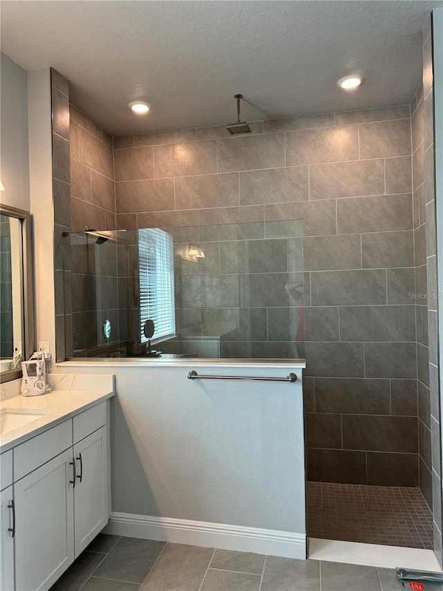 bathroom featuring tiled shower, a textured ceiling, vanity, and tile patterned floors