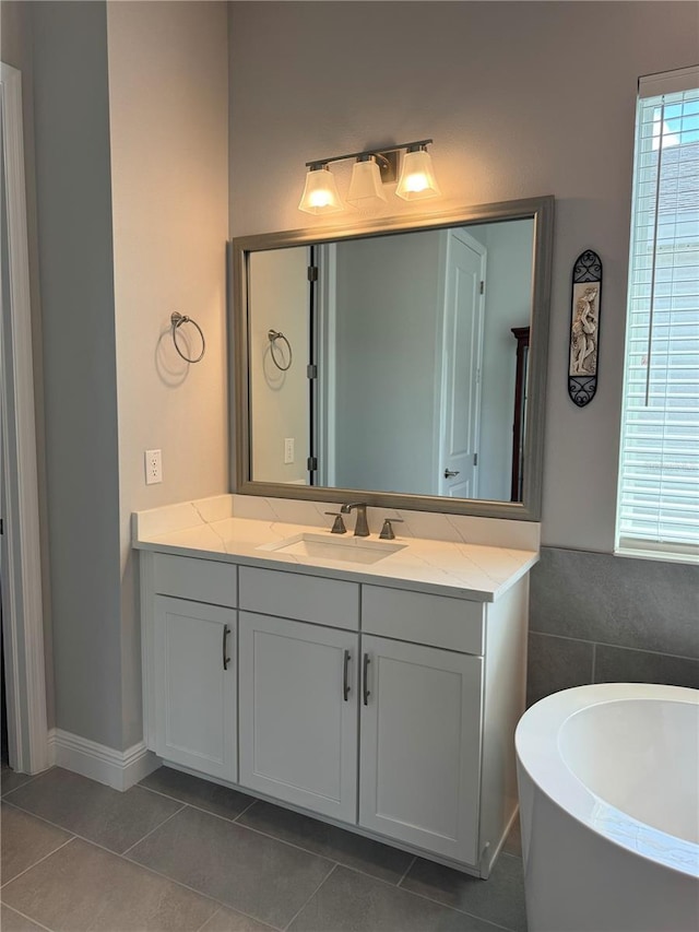 bathroom featuring tile patterned floors, a tub to relax in, vanity, and tile walls