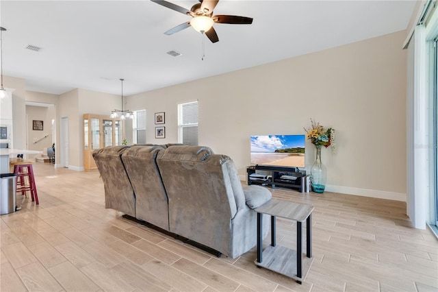 living room with ceiling fan with notable chandelier