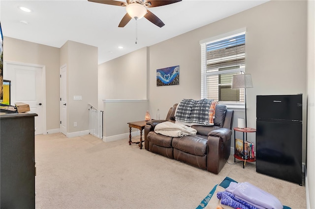 living area with light carpet and ceiling fan