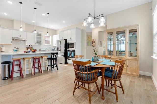 dining space with a notable chandelier, plenty of natural light, and light hardwood / wood-style floors