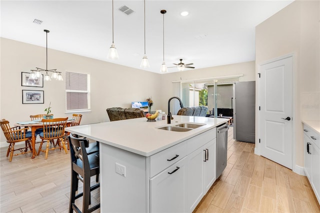 kitchen featuring dishwasher, sink, an island with sink, white cabinets, and ceiling fan with notable chandelier