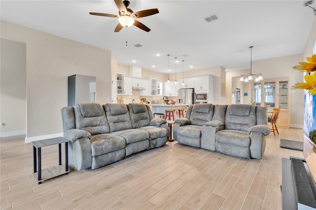 living room featuring ceiling fan with notable chandelier