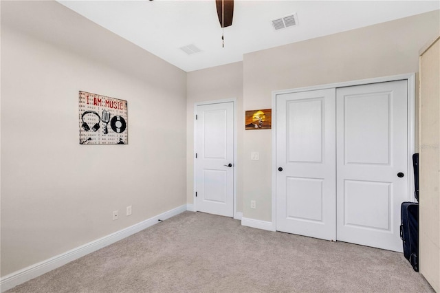 unfurnished bedroom with ceiling fan, light carpet, and a closet