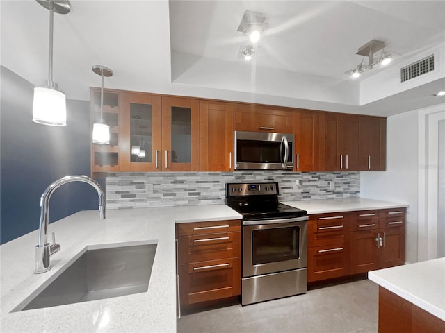 kitchen with backsplash, sink, hanging light fixtures, light stone counters, and stainless steel appliances