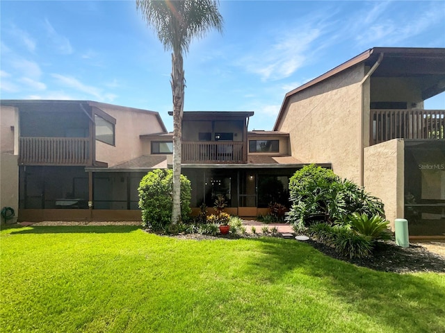 rear view of property with a lawn and a balcony