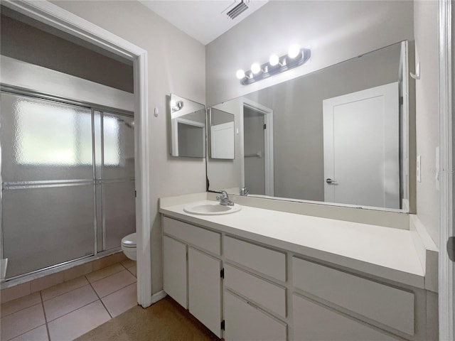 bathroom featuring tile patterned flooring, vanity, toilet, and a shower with shower door