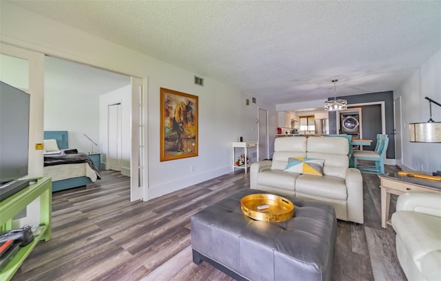 living room with a chandelier, dark hardwood / wood-style flooring, and a textured ceiling