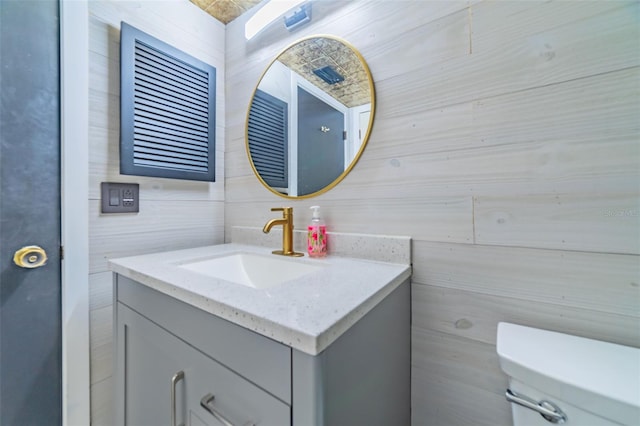 bathroom with vanity, toilet, and tile walls