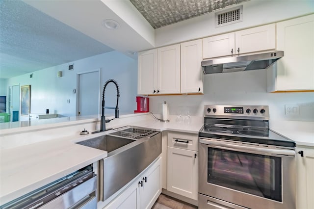 kitchen with appliances with stainless steel finishes, kitchen peninsula, sink, and white cabinets