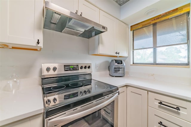 kitchen with electric range and white cabinetry