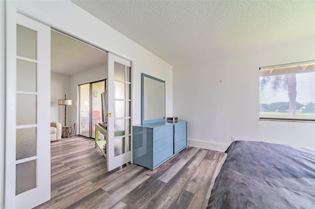 bedroom with french doors, hardwood / wood-style flooring, and a textured ceiling