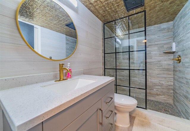 bathroom with tile walls, toilet, a shower with door, and vanity