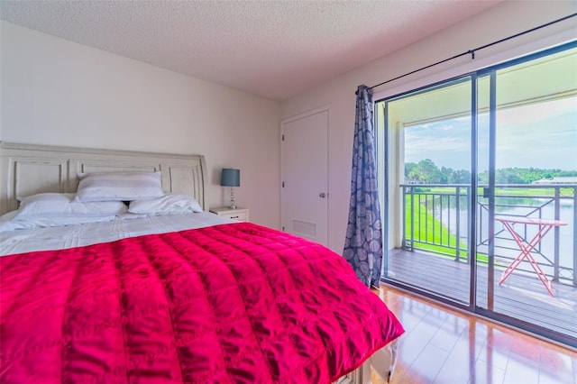 bedroom featuring access to exterior, a textured ceiling, and light hardwood / wood-style flooring