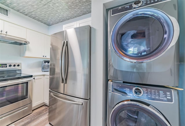 laundry room featuring stacked washer / dryer and light hardwood / wood-style floors