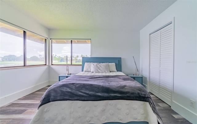 bedroom with a textured ceiling, dark hardwood / wood-style floors, and a closet