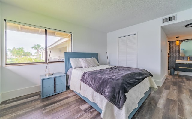 bedroom with a closet, a textured ceiling, and dark hardwood / wood-style floors