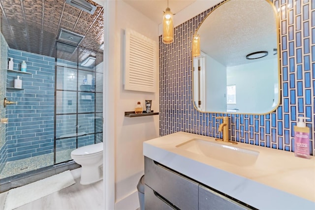 bathroom featuring toilet, vanity, tasteful backsplash, tile walls, and a shower with shower door