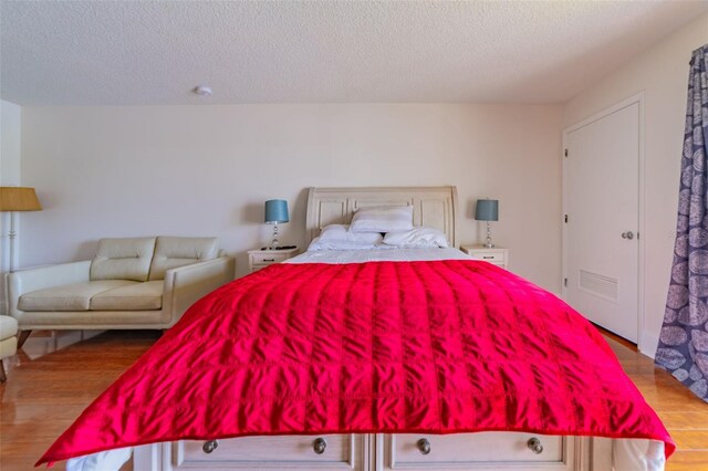 bedroom featuring a textured ceiling and light hardwood / wood-style flooring