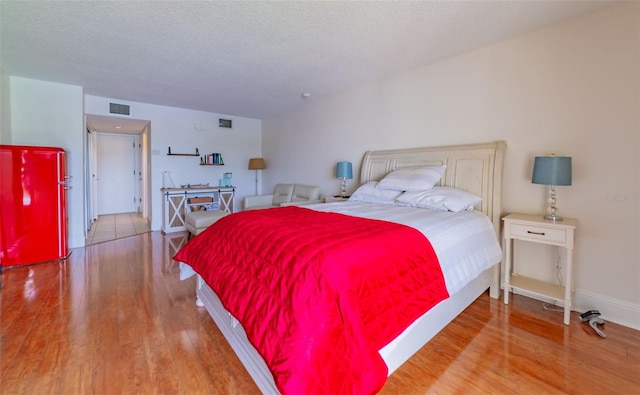 bedroom featuring a textured ceiling and light hardwood / wood-style flooring