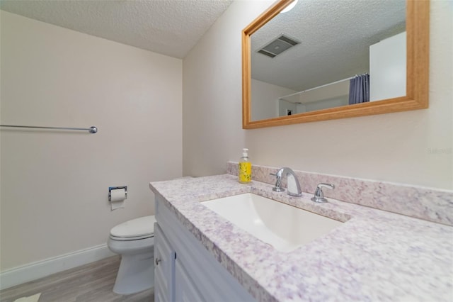 bathroom with wood-type flooring, toilet, a textured ceiling, and vanity