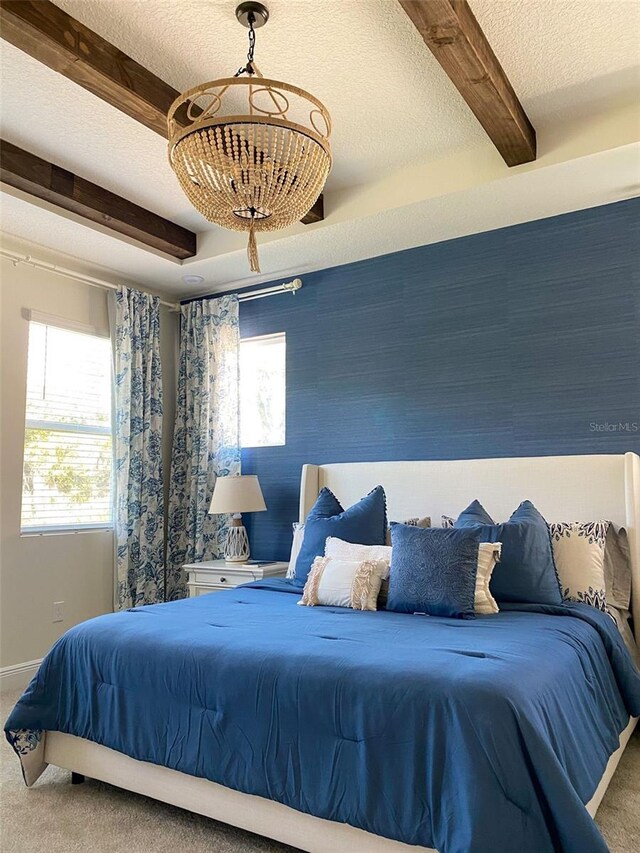 bedroom featuring beam ceiling, carpet, and a textured ceiling