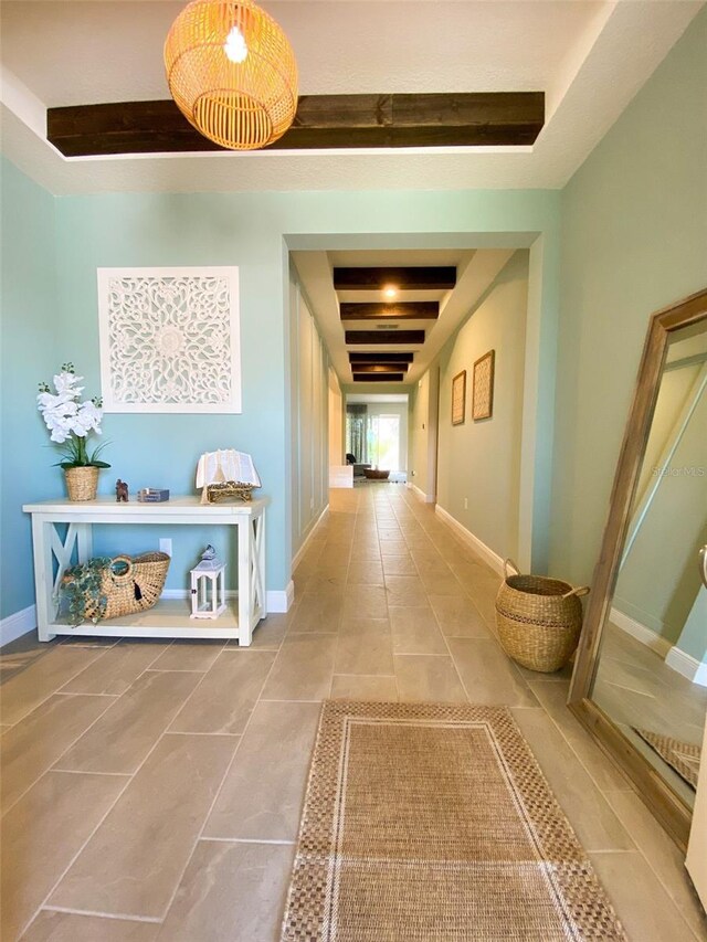 corridor with a raised ceiling, tile patterned floors, and beam ceiling