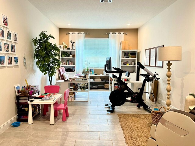 exercise room featuring tile patterned flooring and a textured ceiling