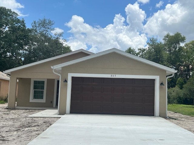 ranch-style house with a garage, driveway, and stucco siding