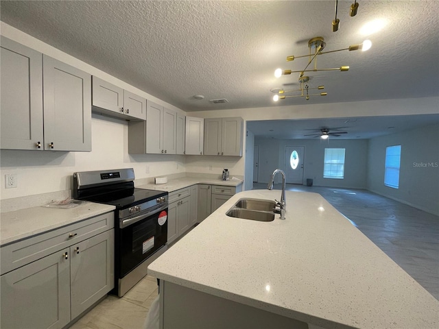 kitchen with a textured ceiling, gray cabinetry, electric range, sink, and ceiling fan