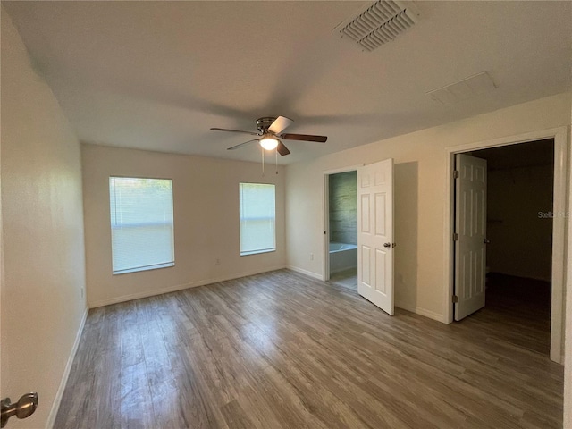 unfurnished bedroom featuring connected bathroom, ceiling fan, and dark hardwood / wood-style floors