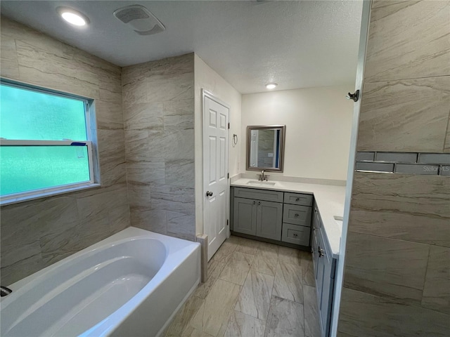 bathroom with a textured ceiling, vanity, tile patterned floors, and a tub