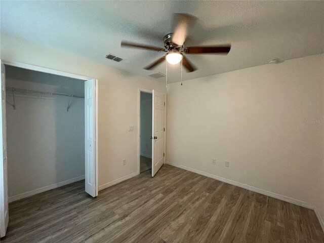 unfurnished bedroom with dark hardwood / wood-style flooring, ceiling fan, and a closet