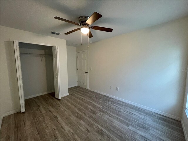 unfurnished bedroom with hardwood / wood-style flooring, ceiling fan, and a closet