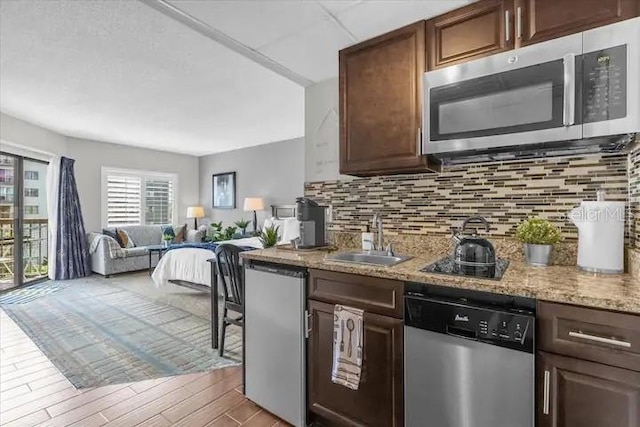 kitchen with light stone counters, sink, dark brown cabinetry, and appliances with stainless steel finishes