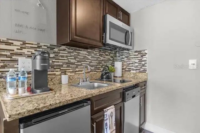 kitchen featuring appliances with stainless steel finishes, sink, dark brown cabinets, and decorative backsplash