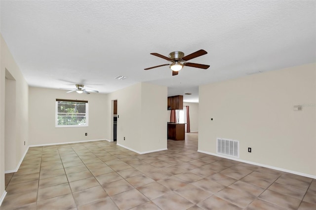 tiled empty room featuring ceiling fan and a textured ceiling