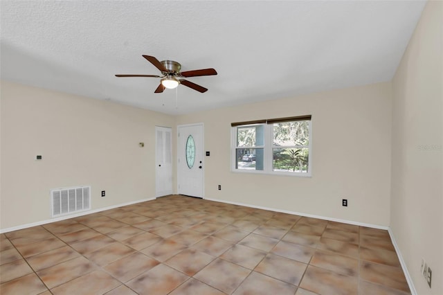 tiled empty room featuring a textured ceiling and ceiling fan