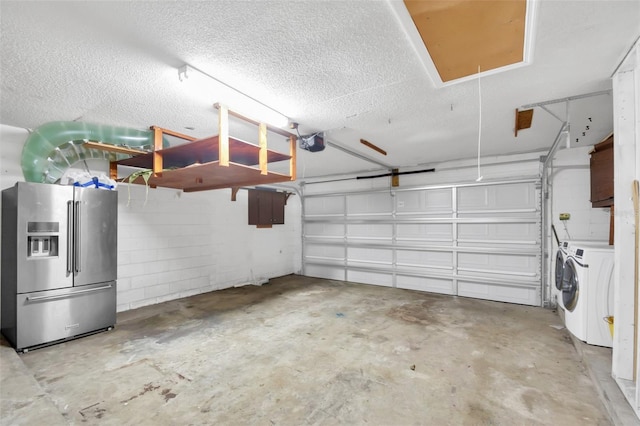 garage with stainless steel refrigerator with ice dispenser, a garage door opener, and washing machine and clothes dryer